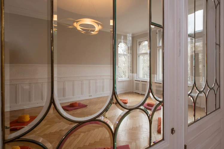 Oberberg Tagesklinik Berlin Kürfürstendamm Blick durch Glastür in einen großen Raum mit Sitzkissen auf dem Boden