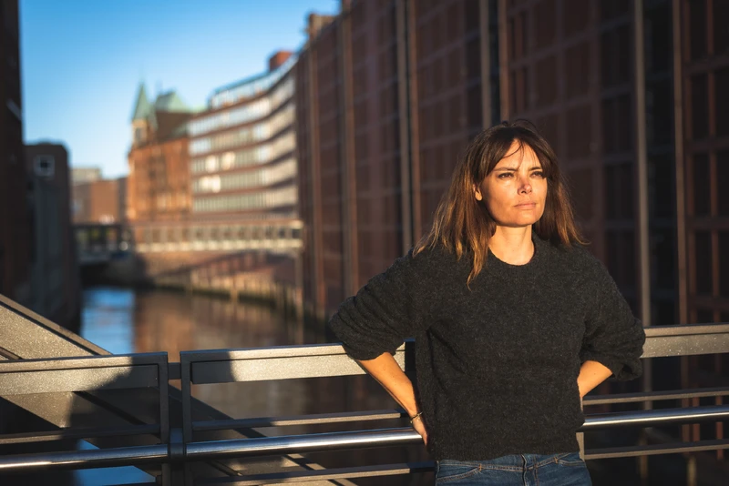 Frau steht an einer Brücke und schaut zur Sonne