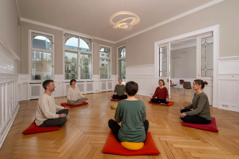 mehrere Personen sitzen im Rahmen einer Entspannungstherapie zusammen