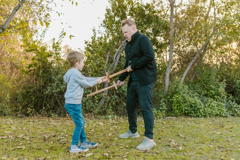 Mann und King spielen mit Holz-Schwertern