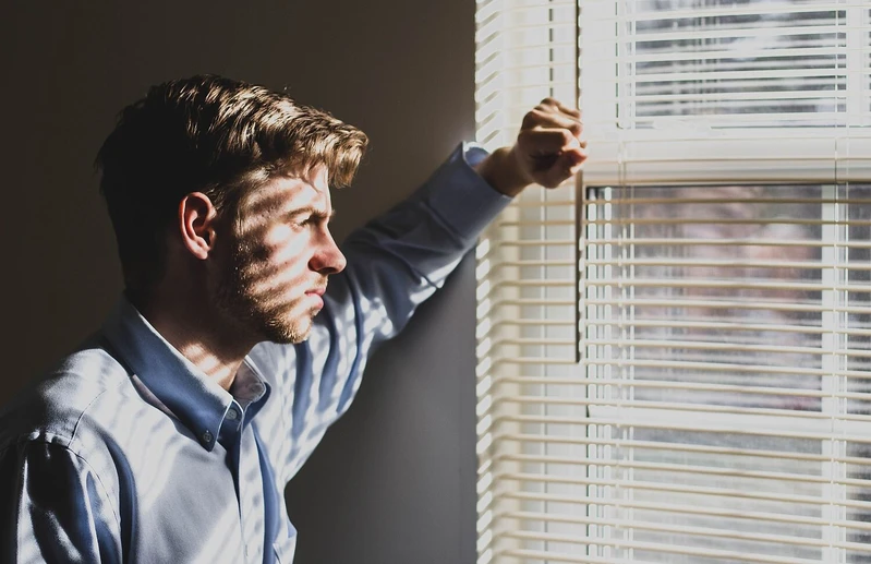 Mann schaut m&uuml;de aus dem fenster