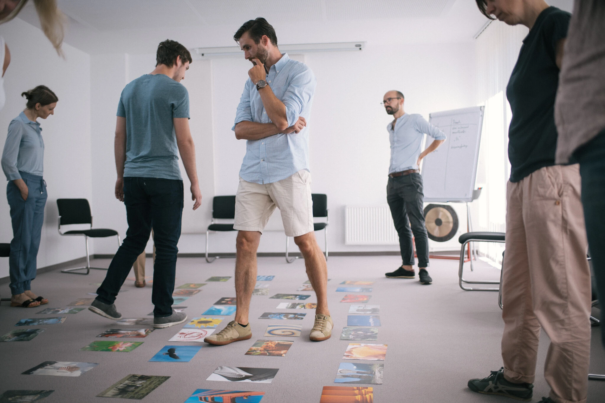 Mann steht in einem raum in mit einer gruppe und schaut auf den boden voller bilder