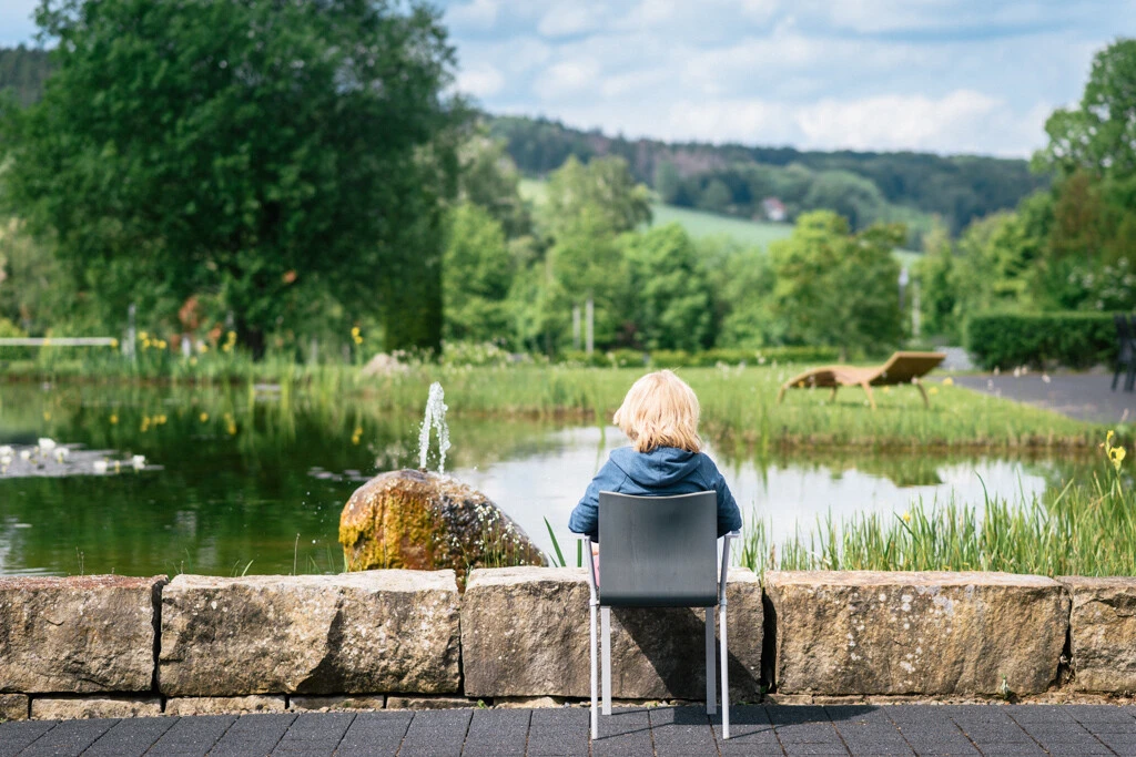 Ältere Frau sitzt am teich und beobachtet die Landschaft