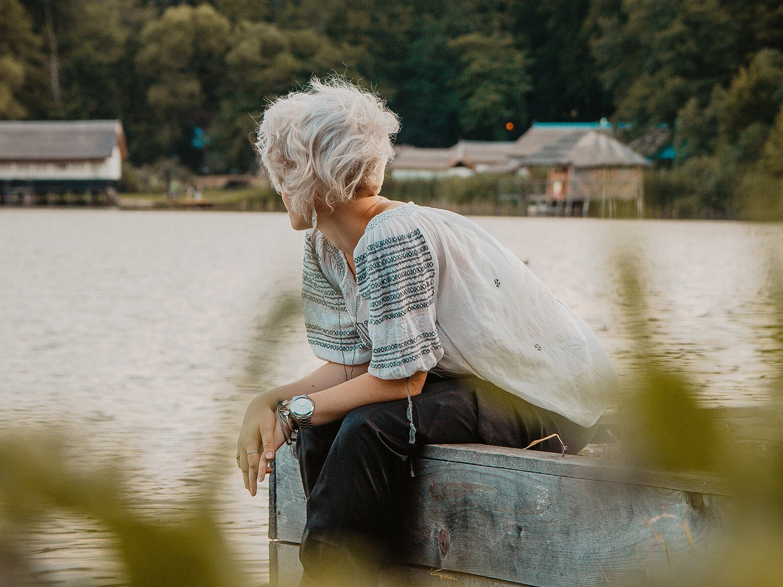 Frau sitzt am see und schaut fern hinaus