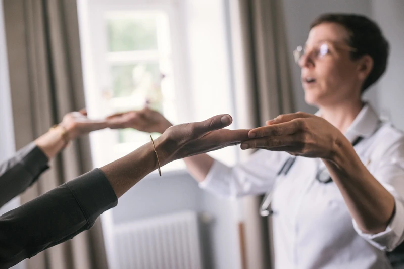 Ärztin hält Hände der Patientin und führt sie durch thepraie