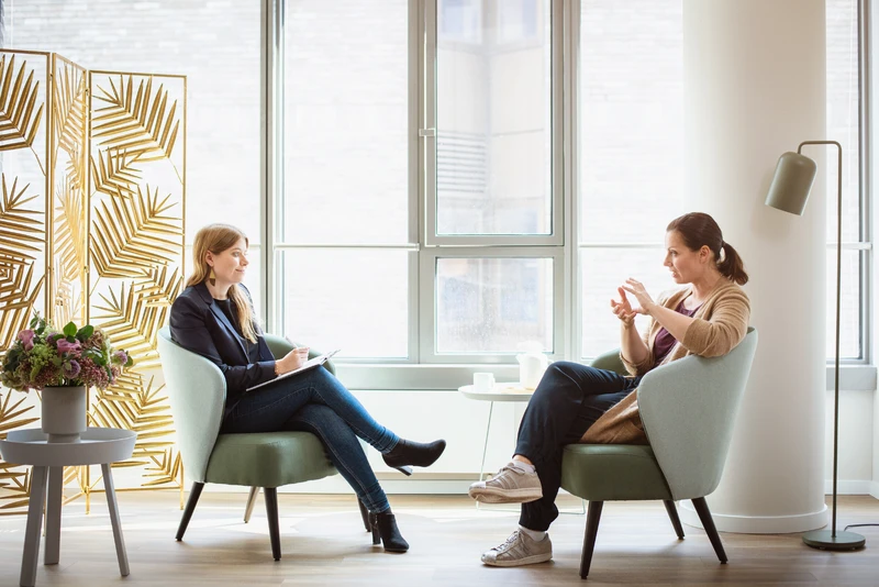 Therapeuting spricht mit patientin im großen raum, beide sitzen gegenüber